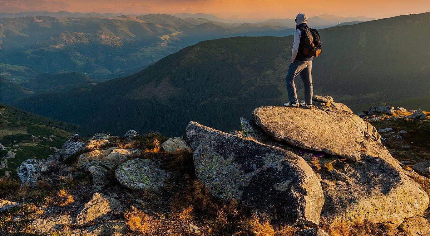 Young man on top of a mountain watching the sunset