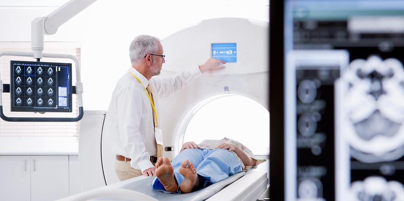Doctor and patient at CT scanner in hospital with digital brain scan in foreground