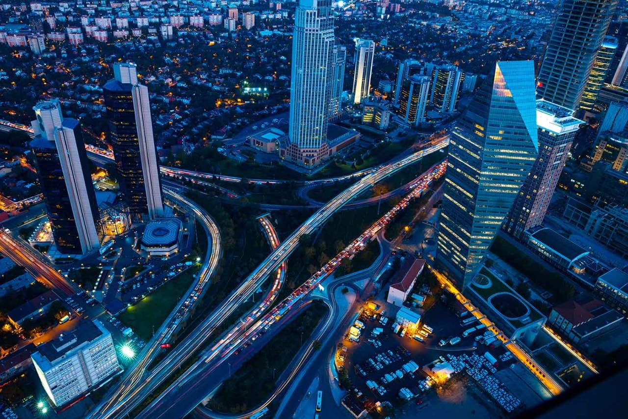 The lights of traffic flow between modern skyscrapers in downtown Istanbul.