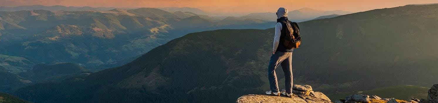 Young man on top of a mountain watching the sunset