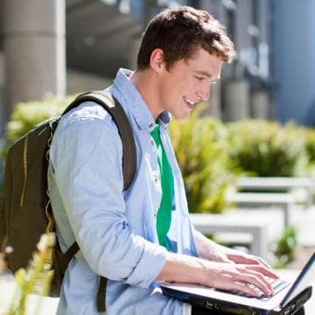 Male student using laptop outdoors