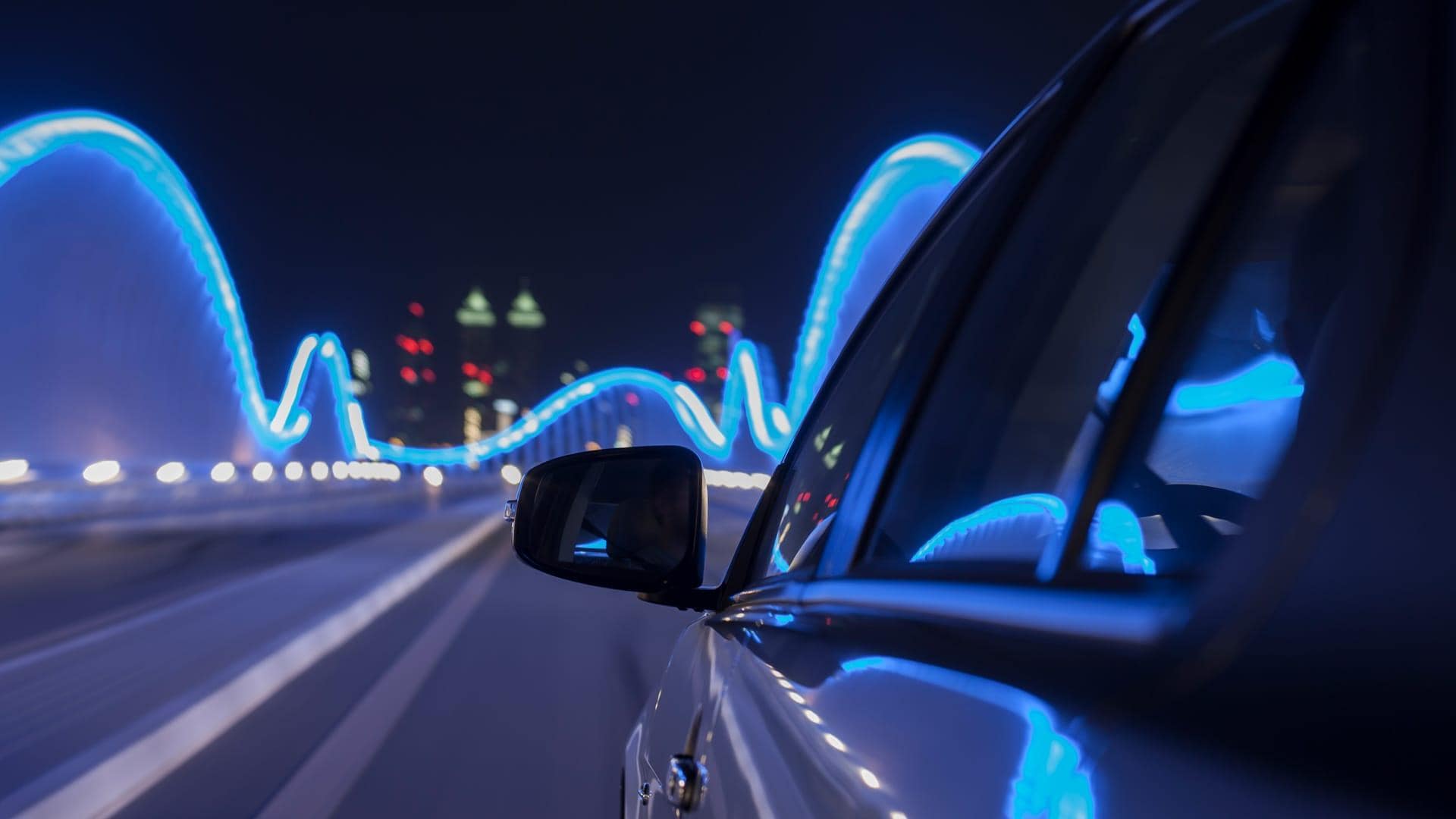 Car driving at night over illuminated bridge