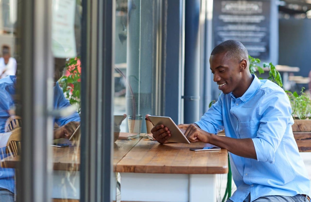 Man working on tablet outside coffee shop