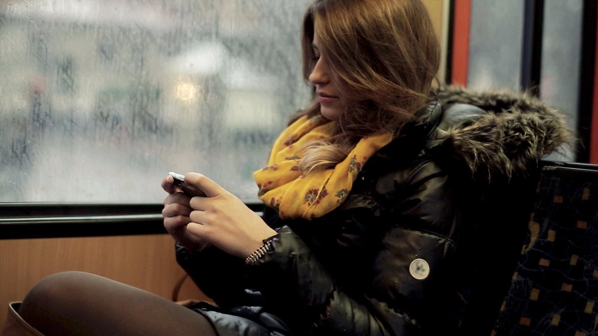 Woman sitting beside window looking at mobile device.