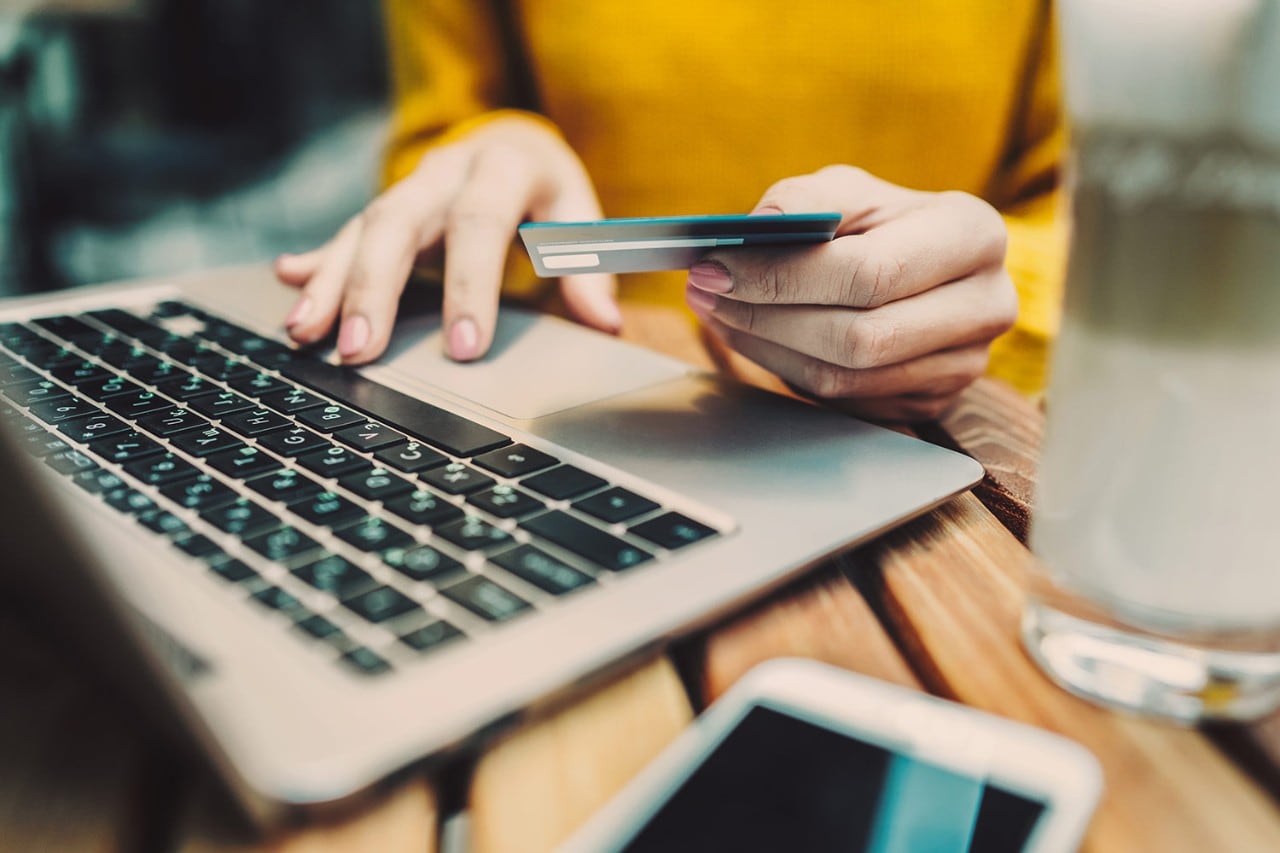 Woman's hand holding credit card and typing on keyboard Woman's hand holding credit card and typing on keyboard