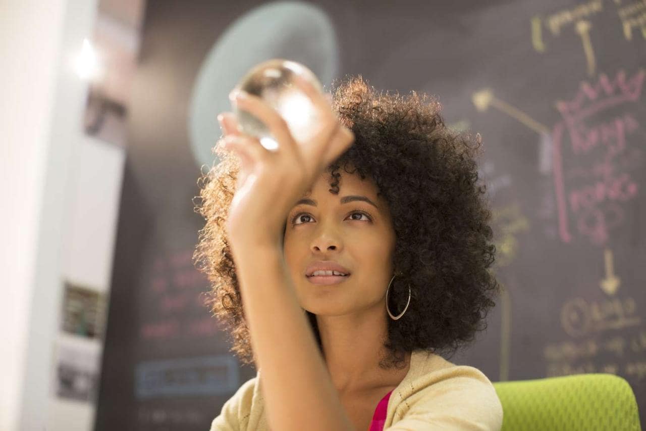 Businesswoman examining crystal ball in office  