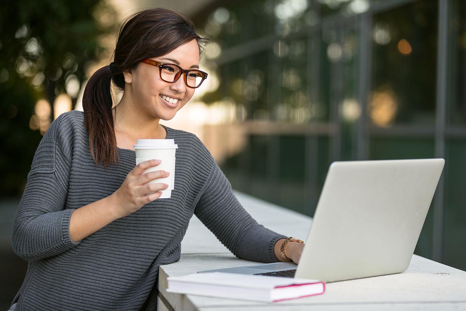 Lady outside on laptop with coffee