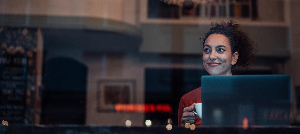 Girl in a coffee shop window with a laptop