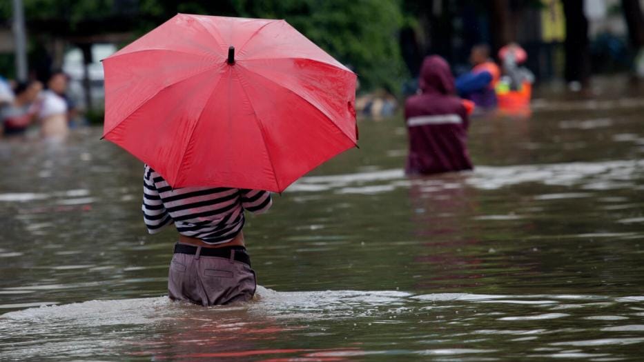 Person wading through flood water with an umbrella