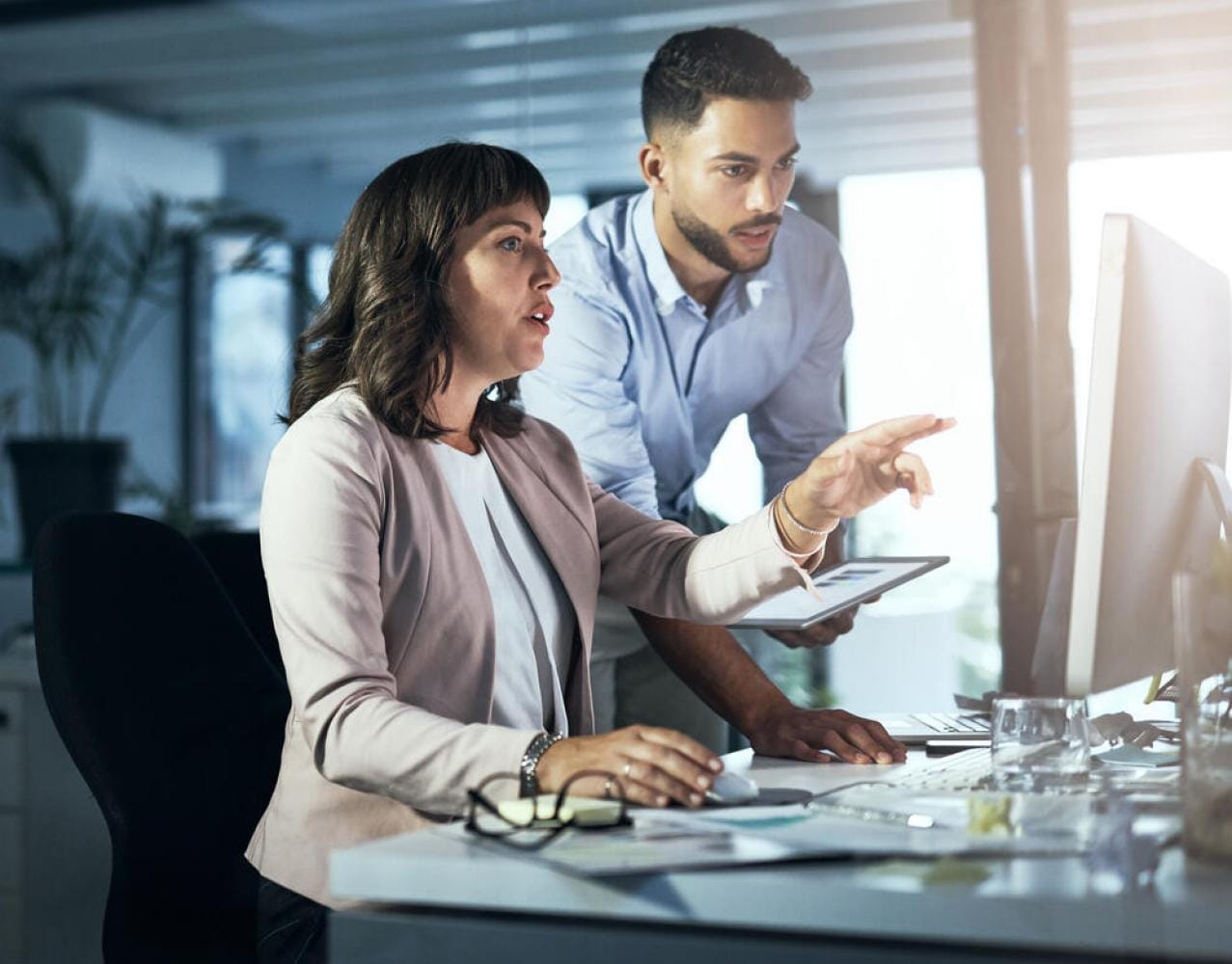Work colleagues point at computer screen