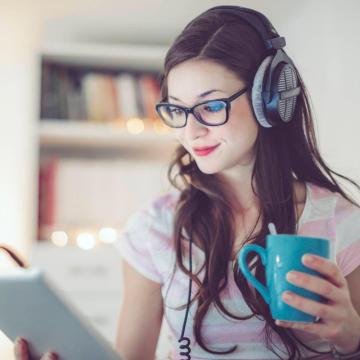 Woman with headphones holding coffee cup
