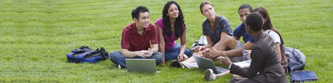 College students and a teacher learning outside on the grass College students and a teacher learning outside on the grass