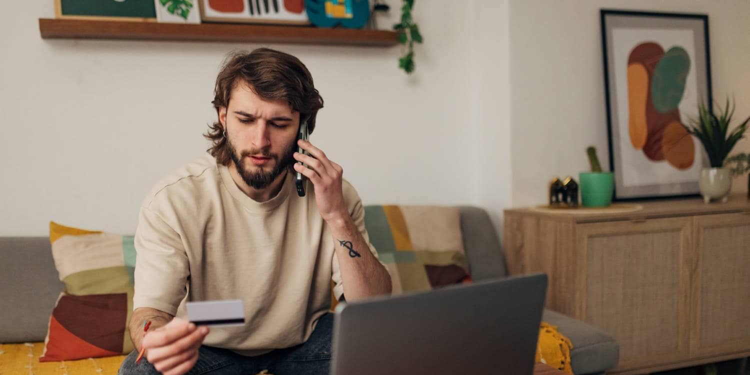 Man looking at credit card and talking on the phone