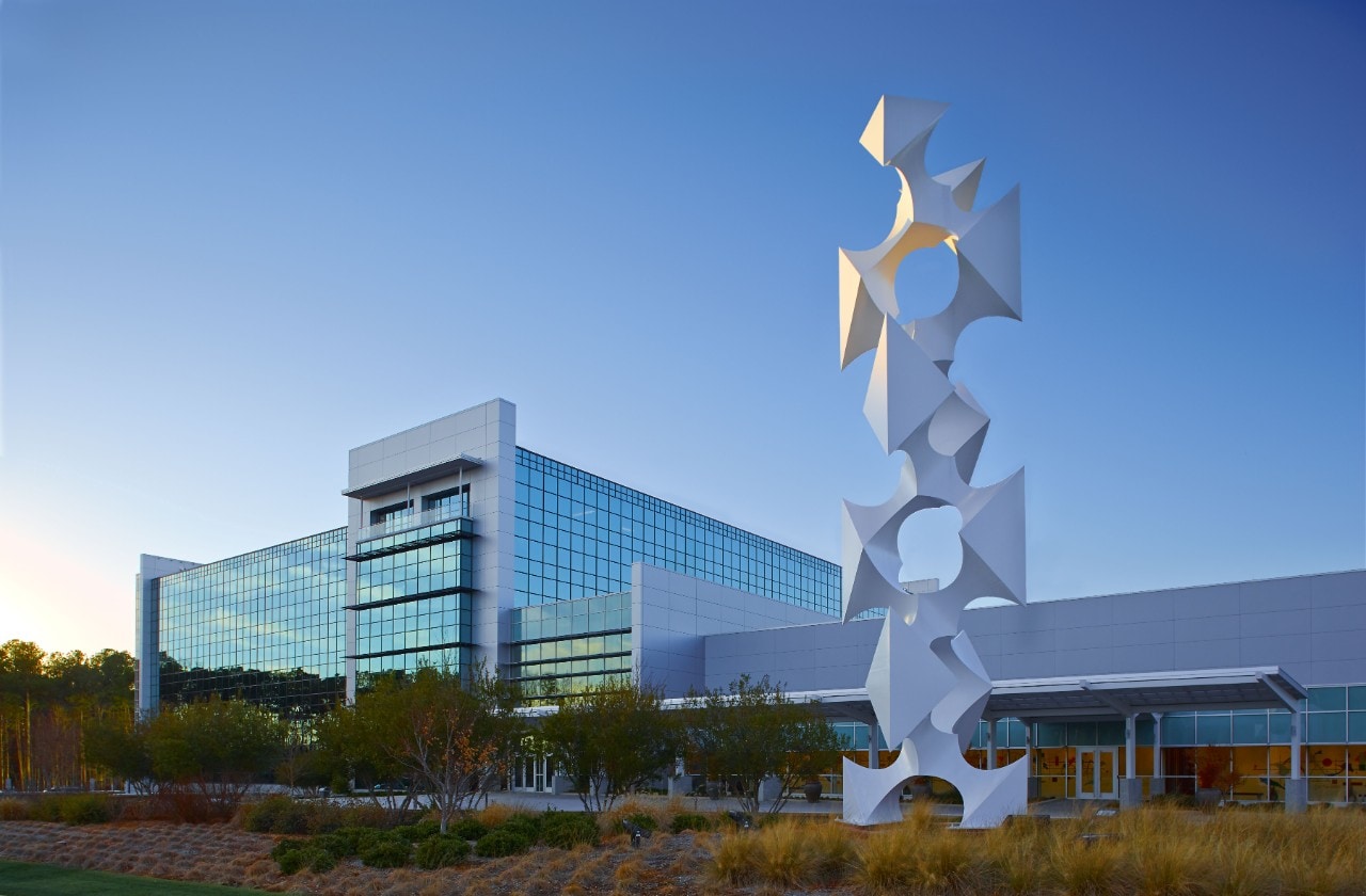 A smart building with a glass exterior and a modern art sculpture in the foreground at SAS headquarters