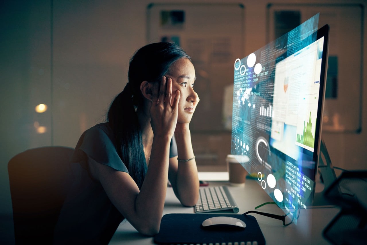 Anxious-looking woman stares at computer screen filled with various confusing data visualizations