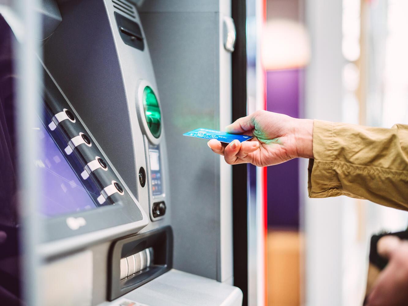 Hand inserting bank card into ATM