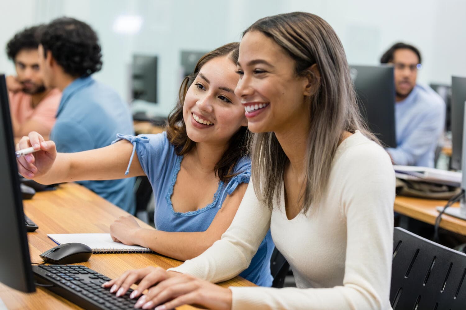 Female coworkers sit near each other and smile while they enjoy 