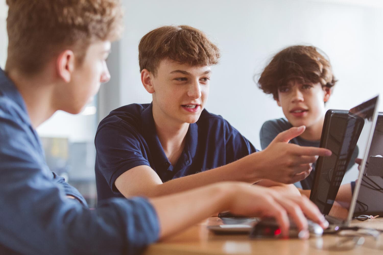 Group of Gen Z teenage boys using laptop during automatic programming lesson