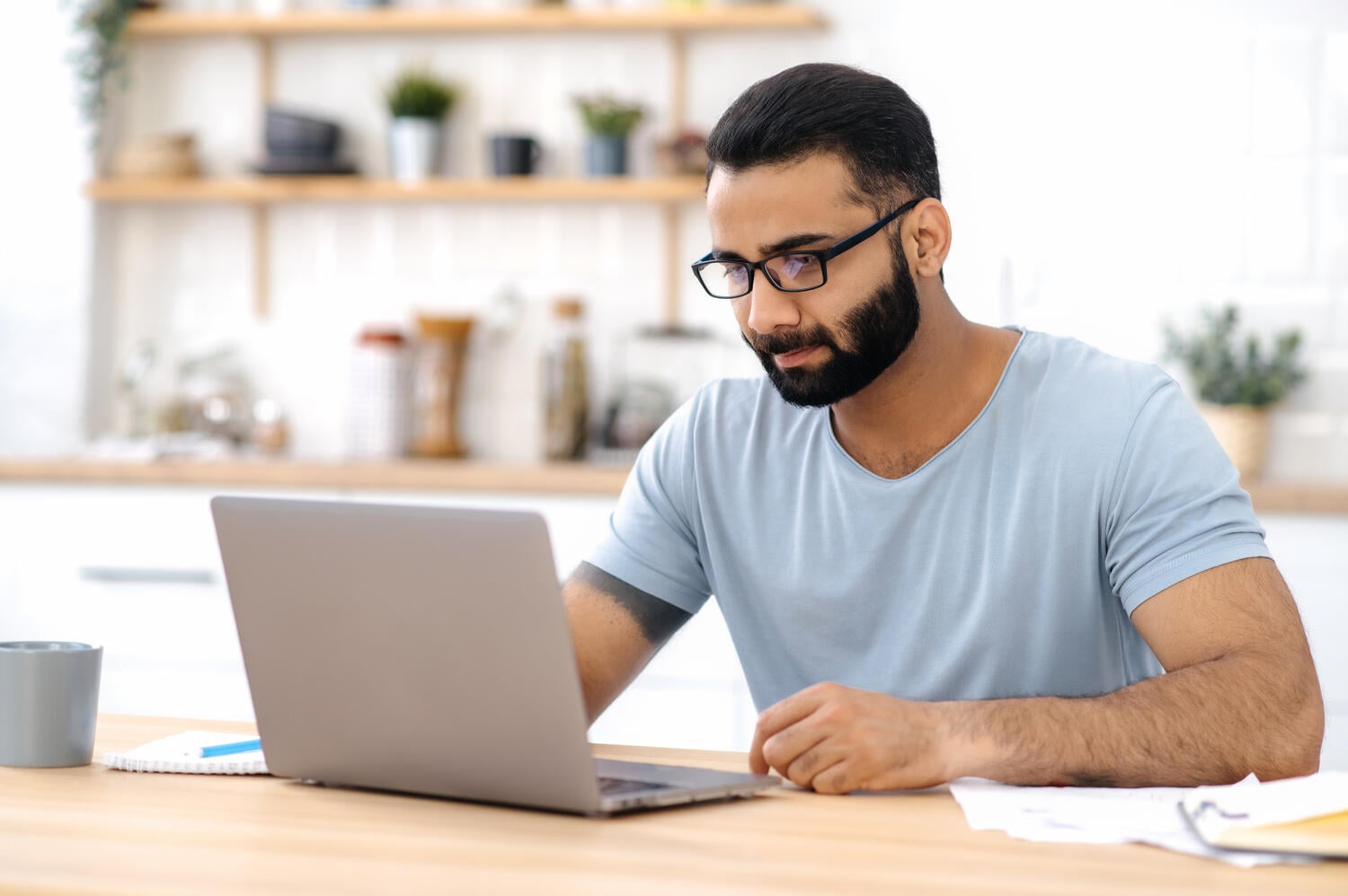 Man wearing glasses and working at his laptop computer
