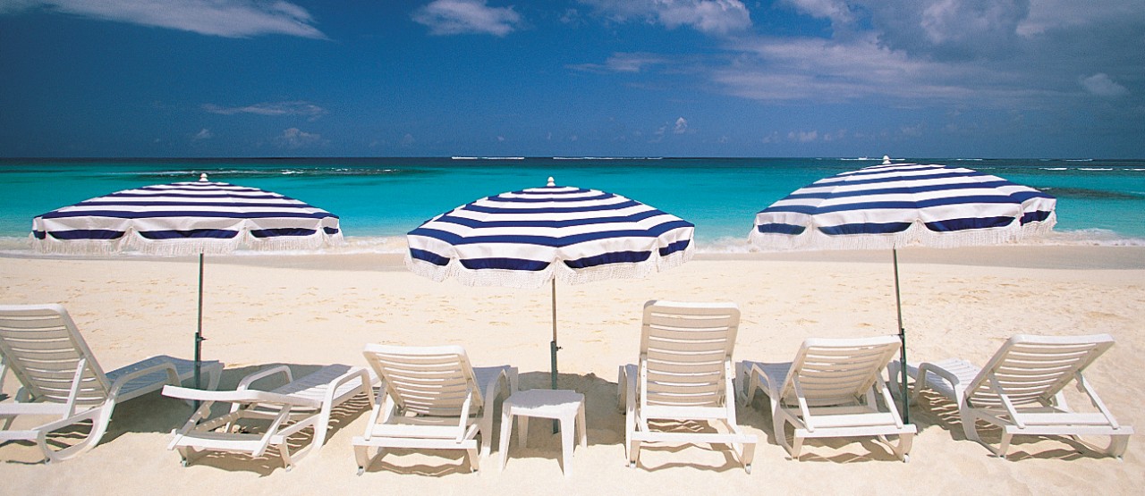 Open beach chairs and beach umbrellas facing ocean