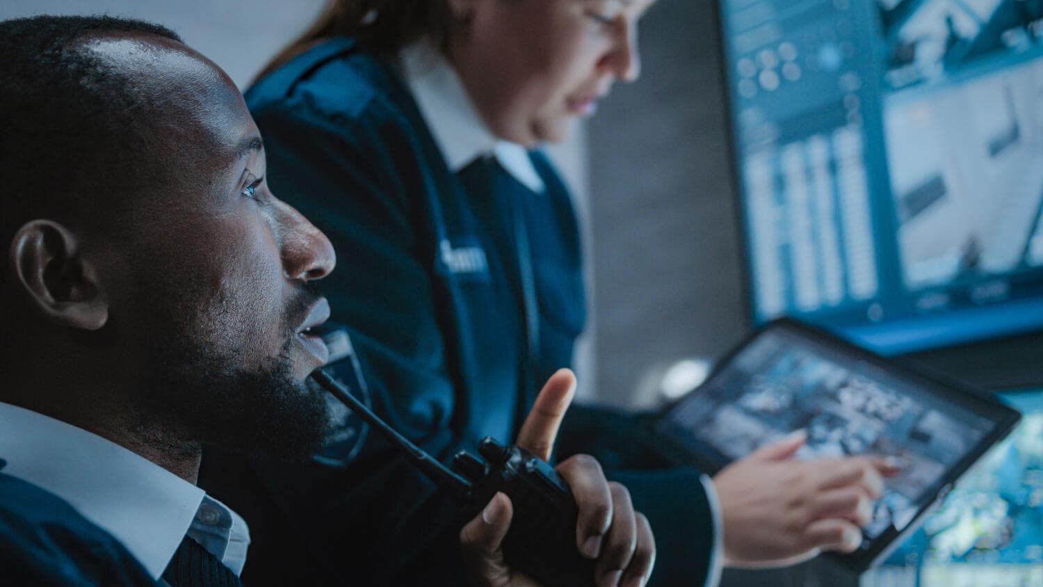 Operators controlling security cameras on screens in a monitoring center