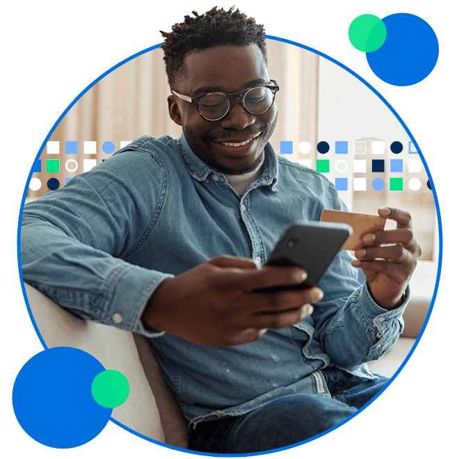 Smiling young man shopping on phone with credit card