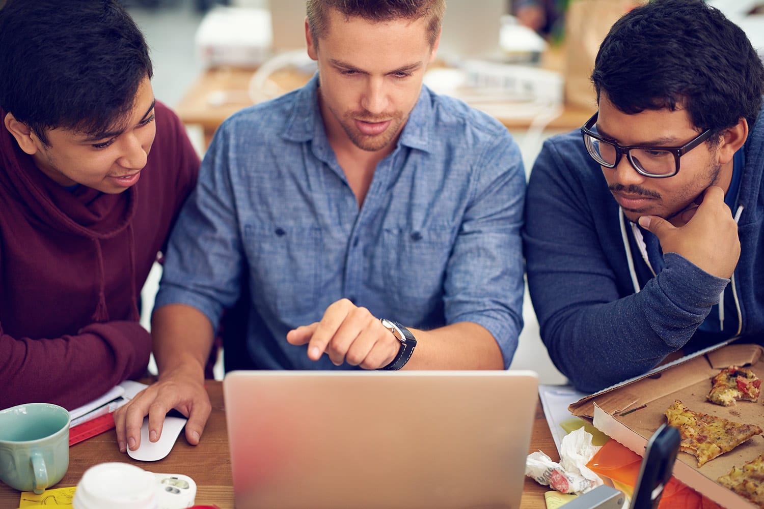 Three young men analyzing data on laptop