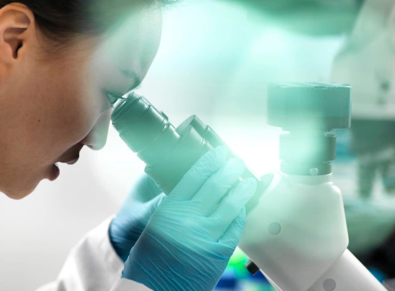 Scientist viewing sample through microscope during