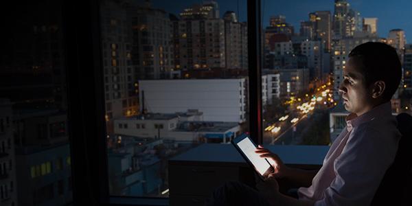 man looking at device with dark city background