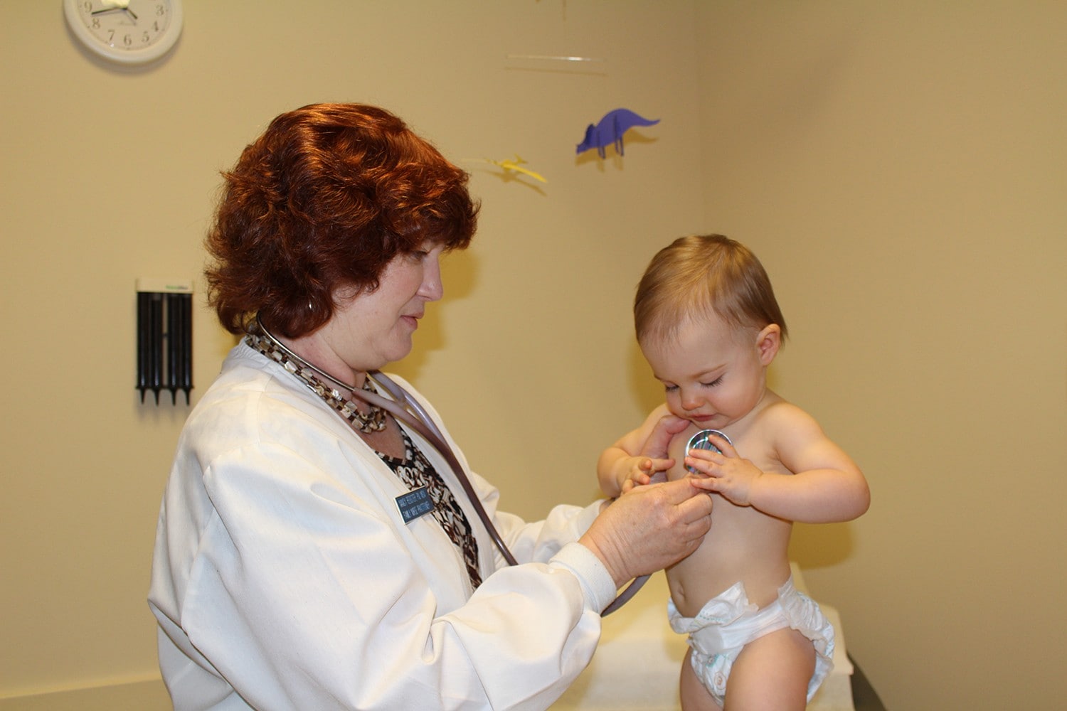 Nurse using stethoscope on baby