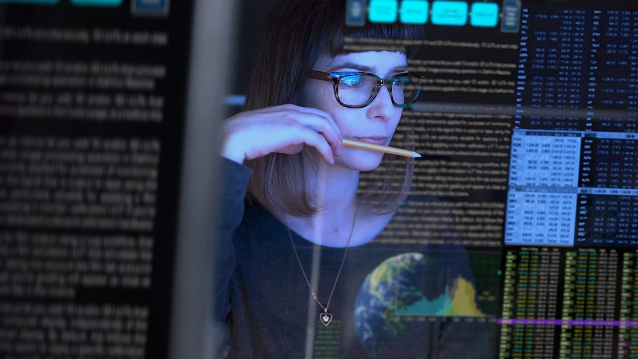 Business woman reads scrolling data reflected in her glasses from a virtual monitor