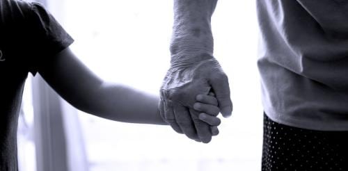 elderly person holding a childs hand