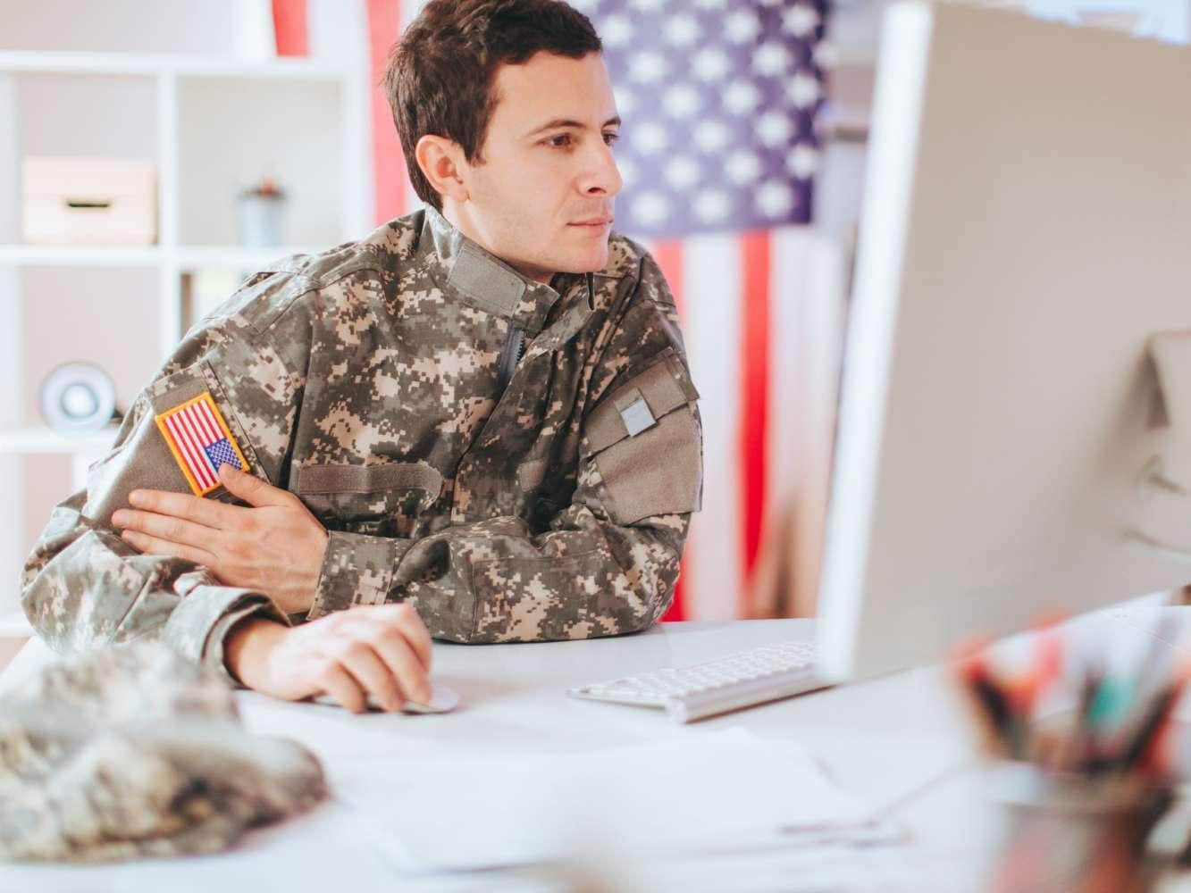 Man in military uniform working on desktop computer