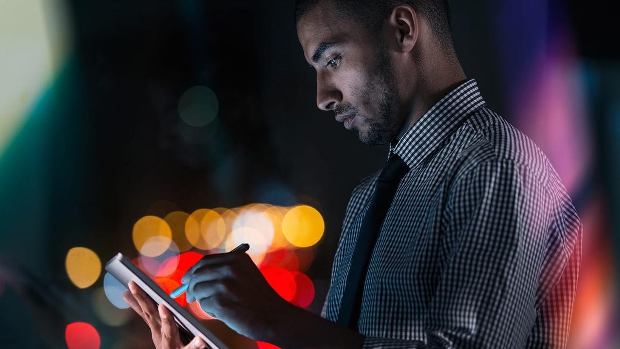 Young businessman using his tablet while working at night