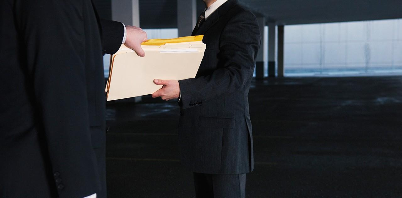 Two businessmen exchanging files – possibly for procurement fraud Two businessmen exchanging files – possibly for procurement fraud
