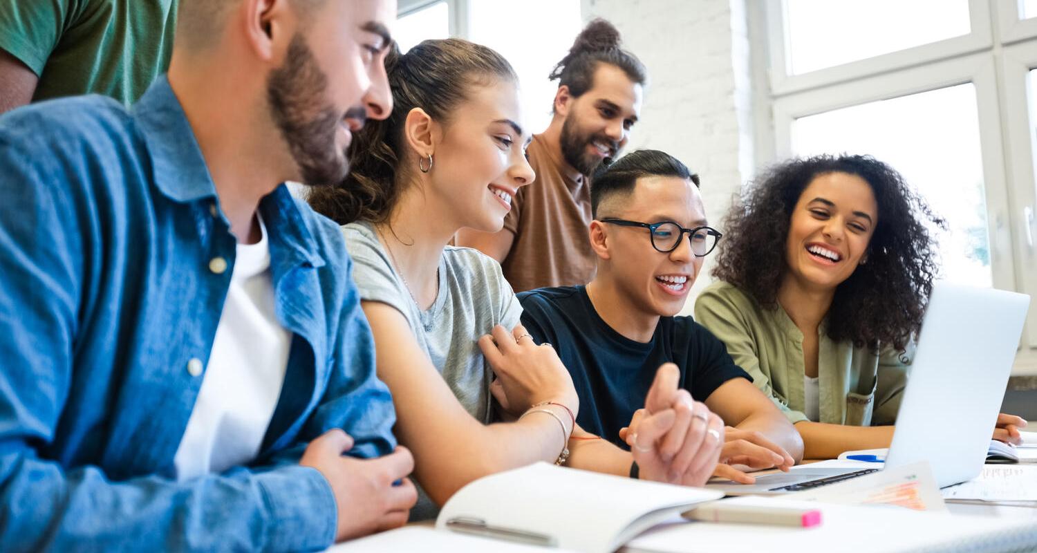 Mixed group of young adults working together around a laptop. Mixed group of young adults working together around a laptop.