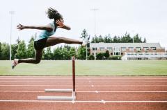 Female athlete in mid-jump over a hurdle