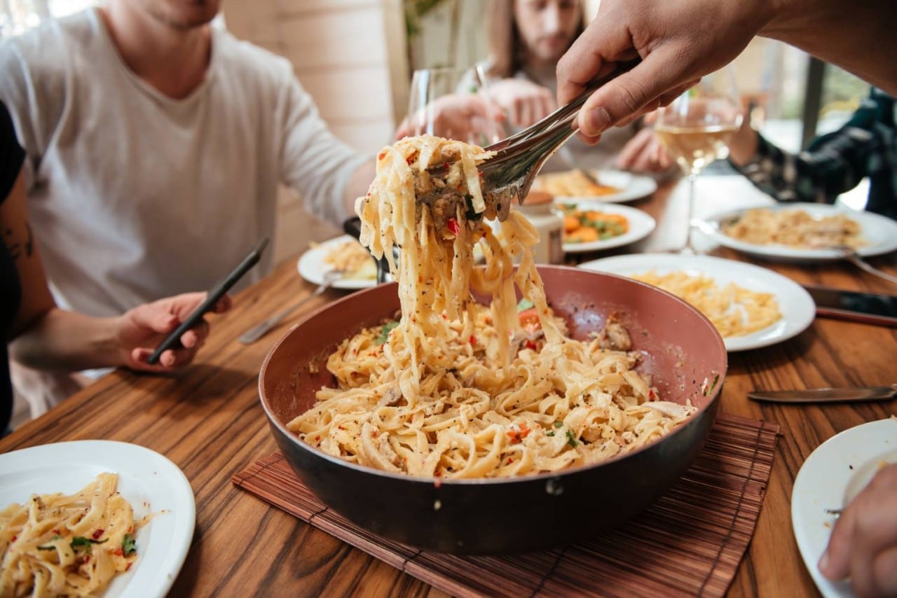 People eating pasta at a kitchen table