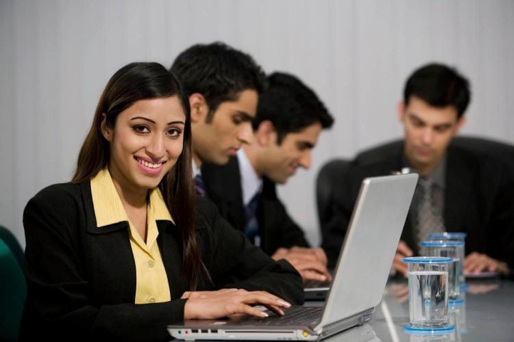 Young group of Indian executives in a team meeting looking at their laptops