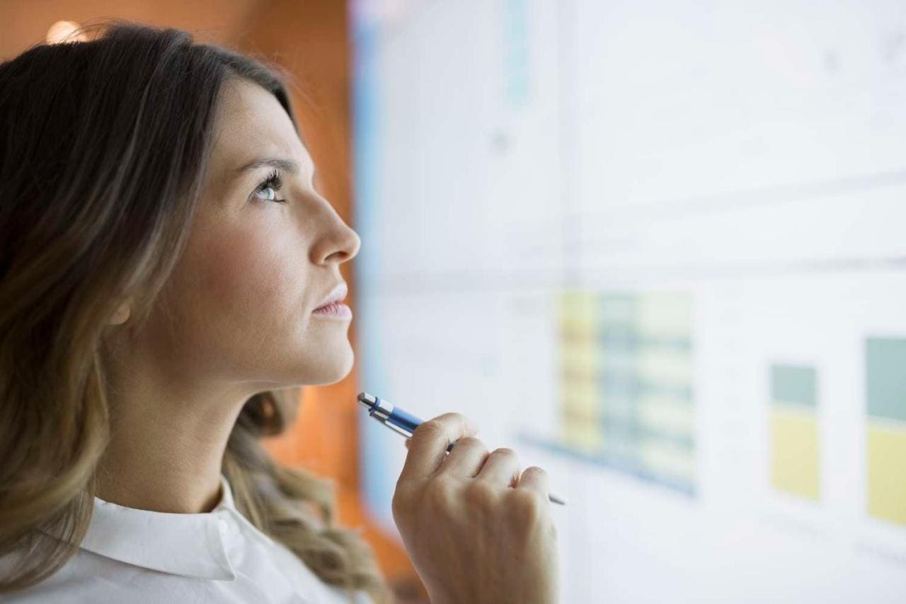 Businesswoman examines charts on projection screen