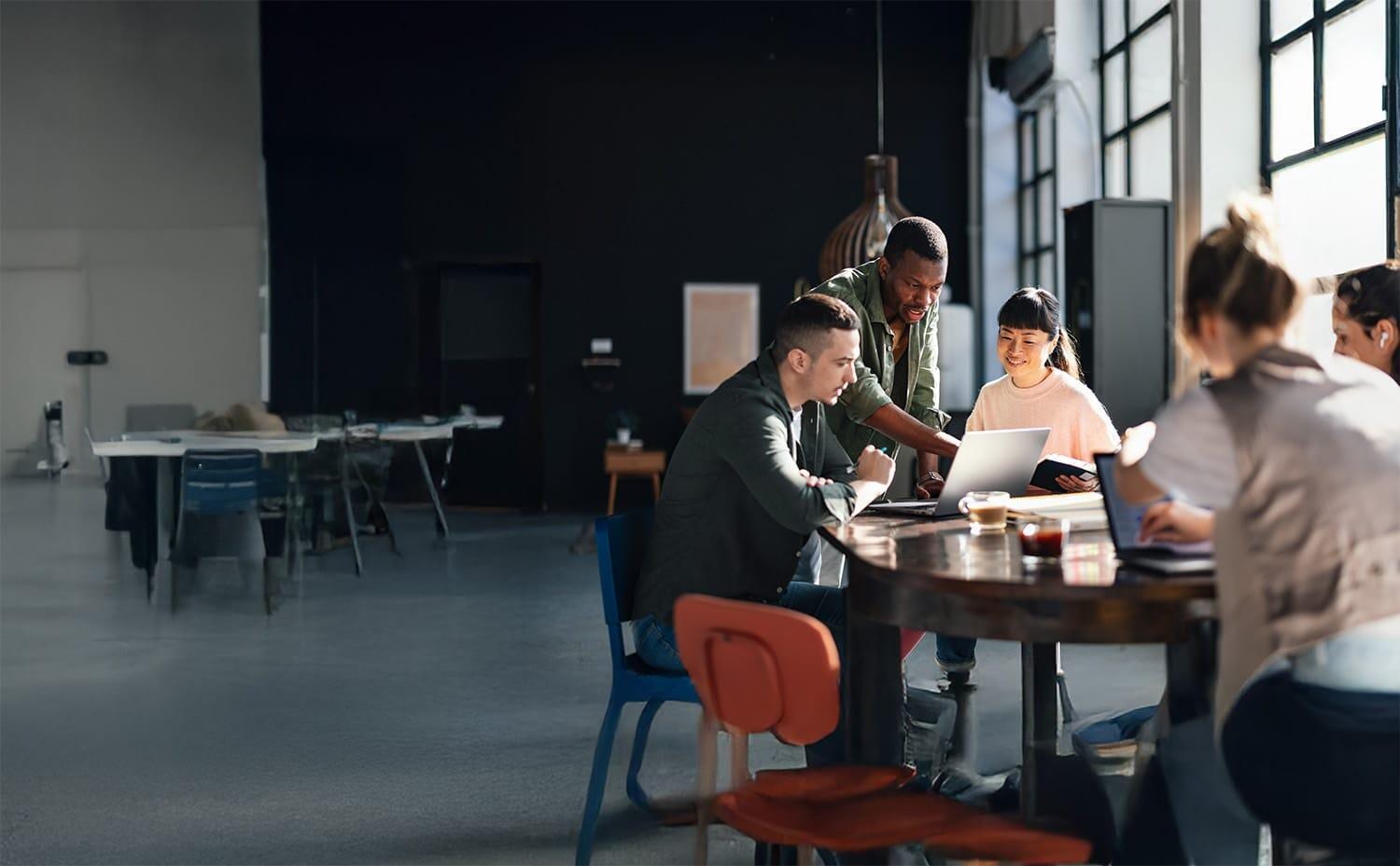 Group of young business people around table in sparsely furnishe