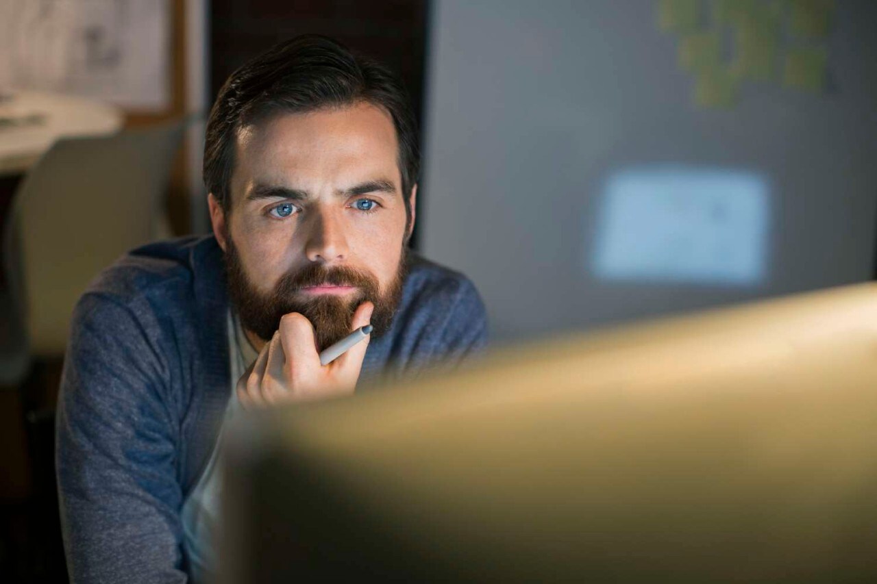 Serious businessman working late at computer in office serious man working at computer