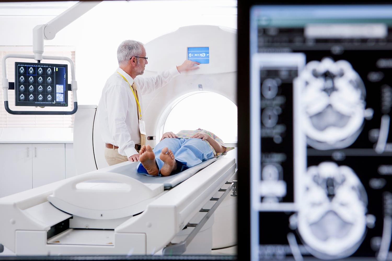 Doctor and patient at CT scanner in hospital with digital brain scan in foreground