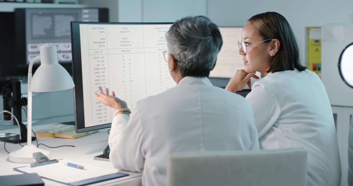 Two women sitting in front of a computer, doing research in a medical laboratory