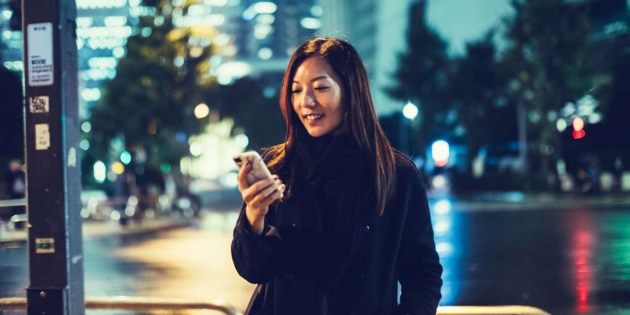 Young Japanese Asian Woman Downtown Tokyo At Night Using Smartphone