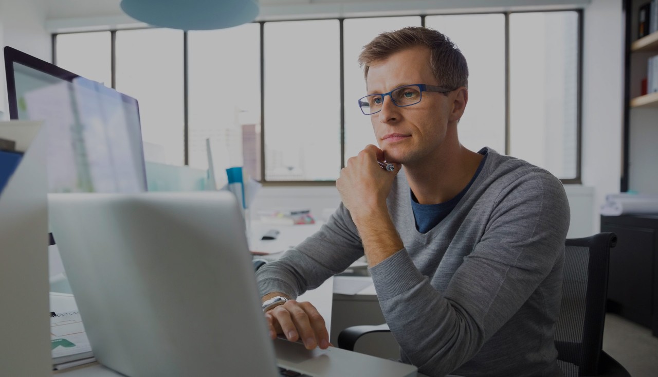 Young business man using laptop and desktop in office