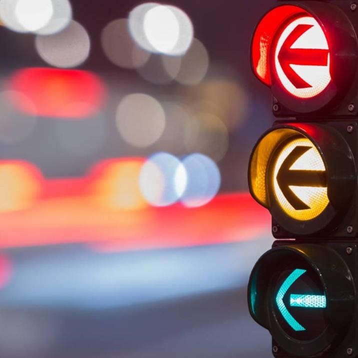 A traffic light with red, yellow and green arrows illuminated.