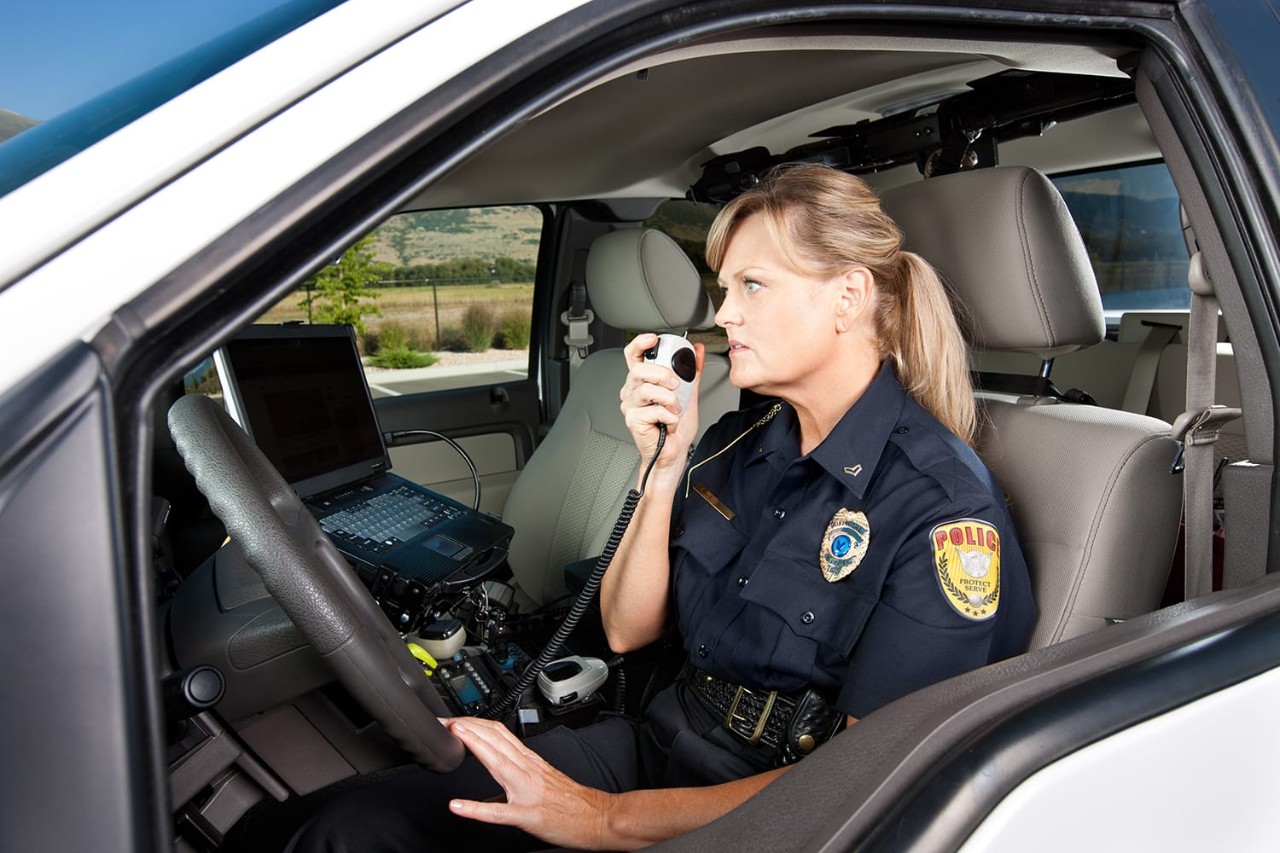 Women officer on radio, sitting in police car