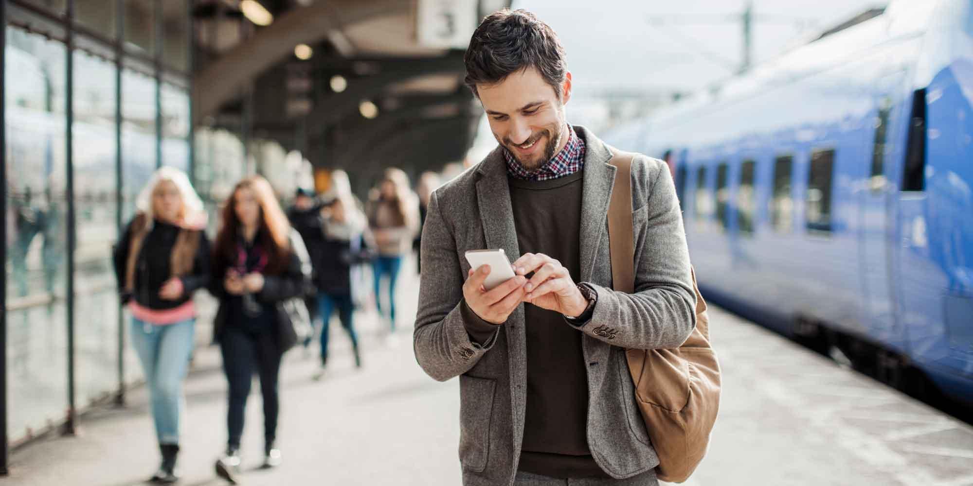 Businessman using mobile phone at train station