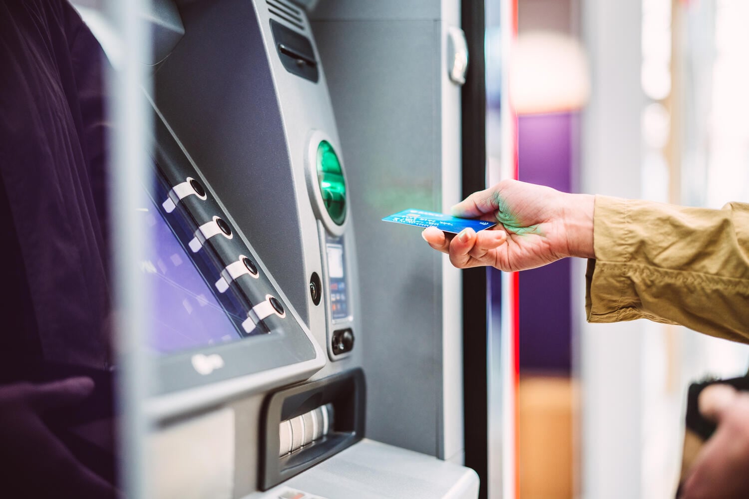 Female hand inserting bank card into ATM